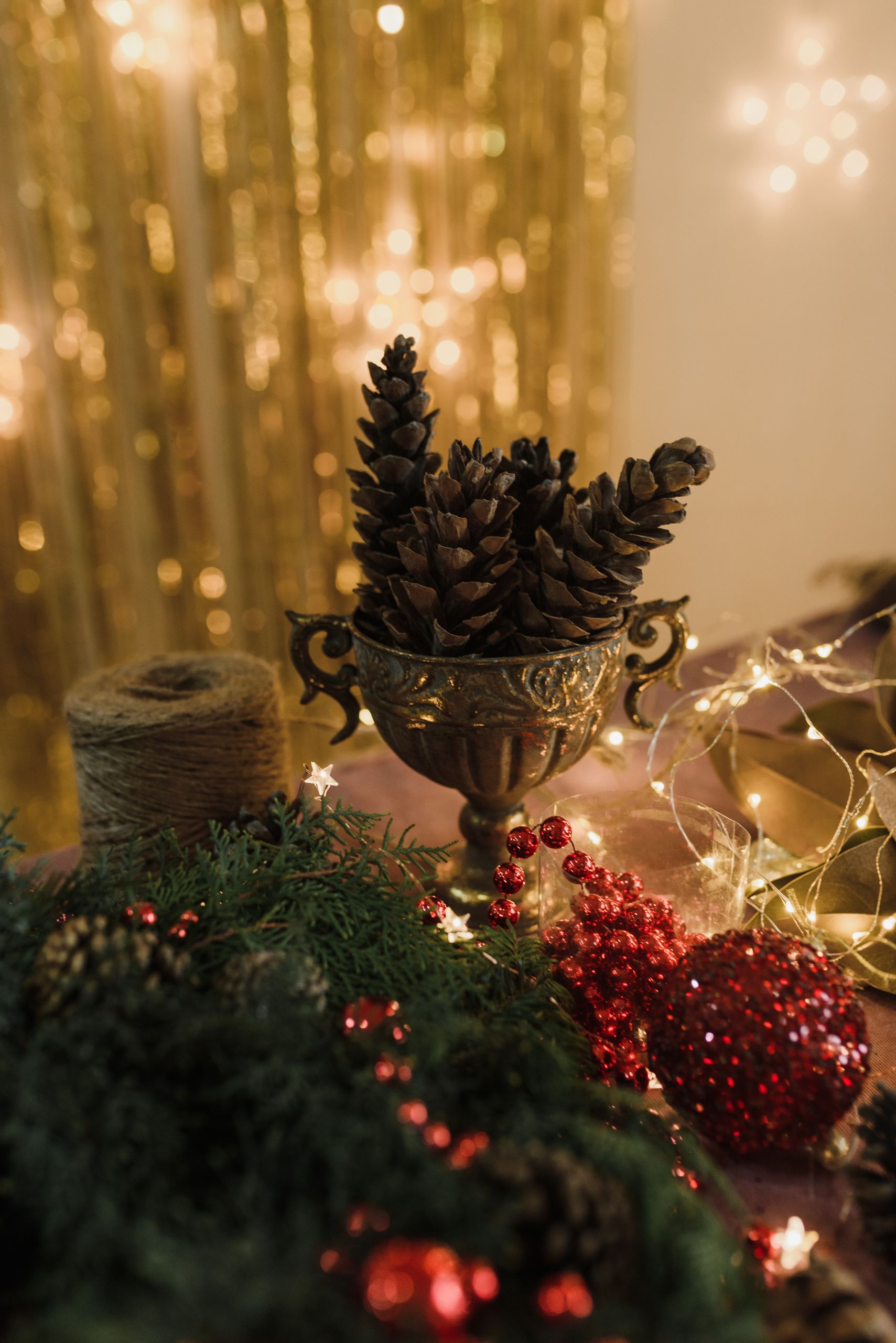 A cozy indoor Christmas scene featuring pine cones, ornaments, and warm lights.